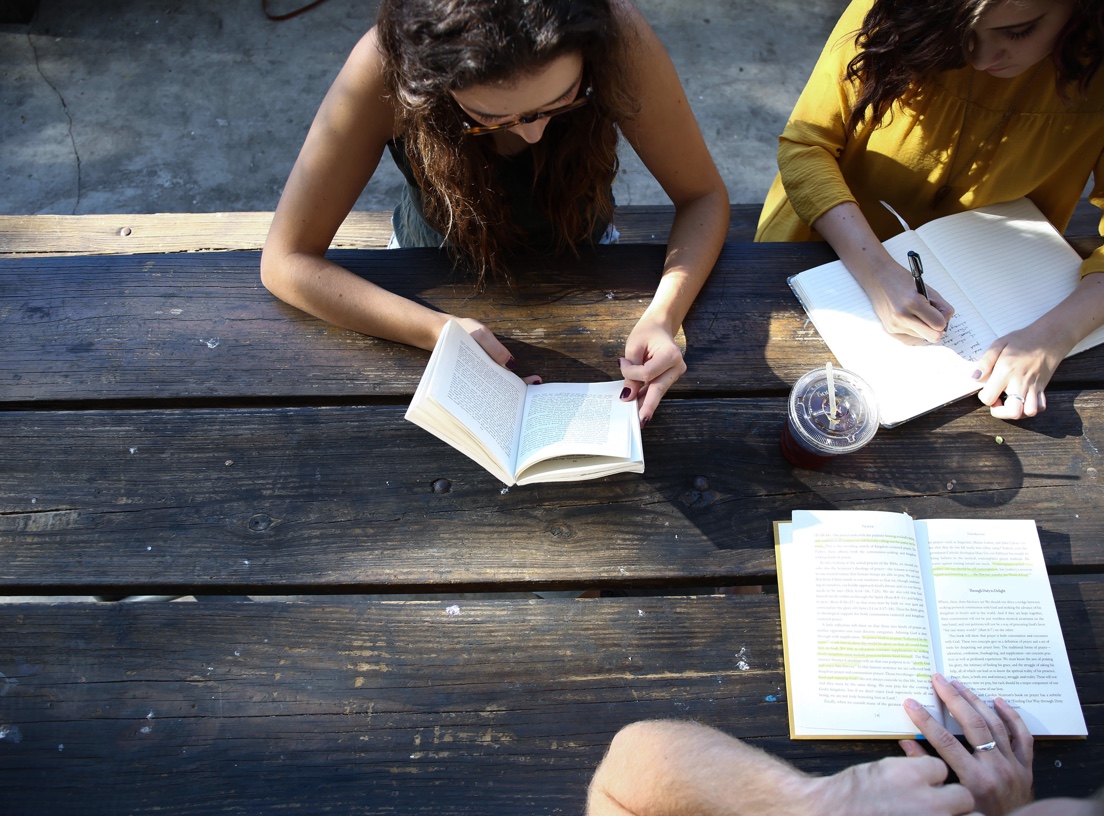 students reading at a picnic table